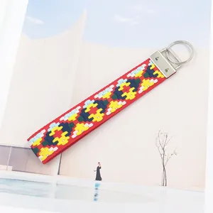 Détail du porte-clés brodé ethnique rouge avec motifs géométriques et fermoir argenté