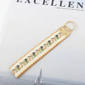 Dettaglio del ricamo floreale sul cinturino jacquard da 25mm con moschettone dorato