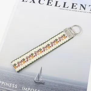 Dettaglio di un portachiavi in tela ricamata con fiori da 25 mm e anello in metallo argento