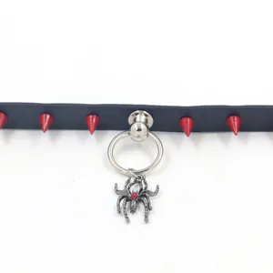 Detail of red punk spikes and silver spider pendant with red gem on black leather collar