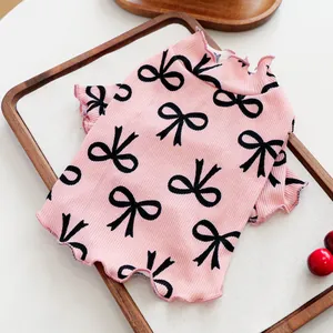 Detail view of pink ribbed knit pet shirt with black bow patterns and ruffle hem