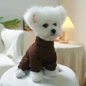Close-up of brown waffle knit dog onesie on a white Bichon Frise in a cozy home setting