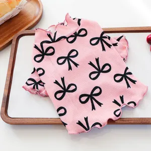 Macro view of pink ribbed pet shirt with black bow prints and ruffled edges detail