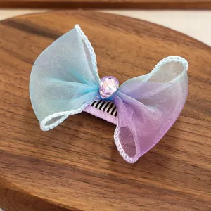 Gros plan d'une pince à cheveux avec nœud en organza dégradé bleu violet et gemme