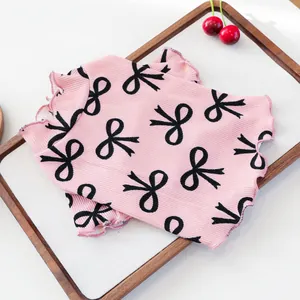 Close-up of pink ribbed dog shirt featuring black bow prints and ruffled edges