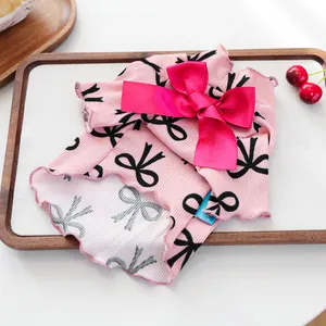 Detail of pink pet vest with black bow pattern and ribbed fabric texture for small dogs