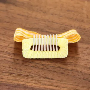 Détail de pince à cheveux pour chien avec nœud à carreaux orange et blanc