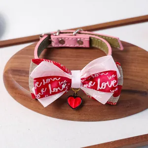 Détail du collier pour chat en cuir rose avec nœud et pendentif cœur sur plateau bois