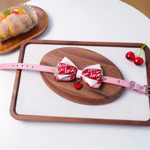 Détail d'un collier rose pour animaux avec un nœud double et un pendentif cœur