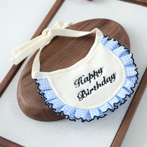 Detail of knit pet bib with blue plaid ruffle and Happy Birthday embroidery