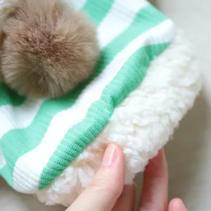 Close-up of pet striped hoodie with cozy sherpa lining and fluffy brown pompom ball