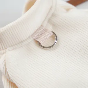 Close-up of cream knit pet sweater with vertical ribbing and silver metal D-ring for leash