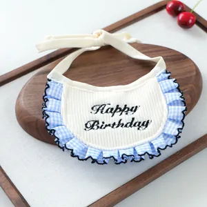 Detail of pet bib with Happy Birthday embroidery and blue gingham ruffled lace edge