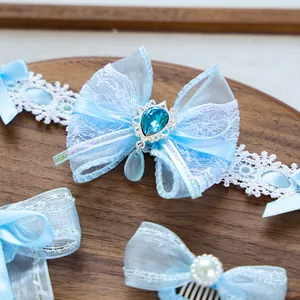 Blue pet bow accessory with lace and blue teardrop gemstone on a wooden tray