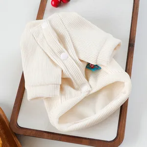 Macro detail of cream knit pet sweater featuring snap buttons and ribbed texture