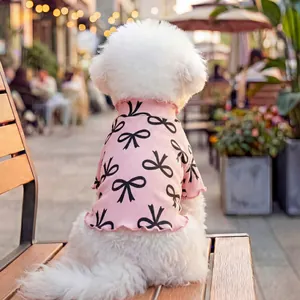 Pink pet T-shirt with black bow prints and ruffled edges worn by a small white dog