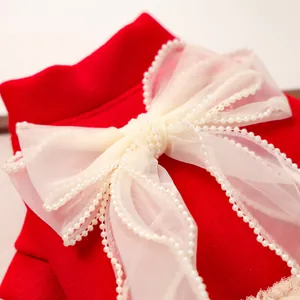 Dettaglio di un vestito rosso per animali in tweed con fiocco in organza e perle