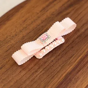 Détail de la pince à cheveux nœud rose avec pierre précieuse factice et perles