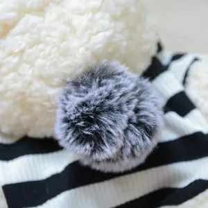 Detailed close-up of a fluffy pom-pom and striped knit fabric for winter pet hoodies