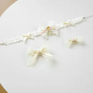 Detail of lace pet collar and bow clips set with yellow gems and pearls for cats