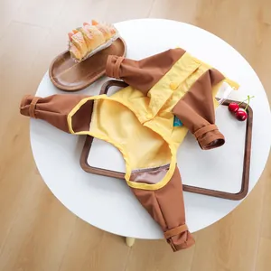 Detail view of yellow and brown waterproof pet jumpsuit with velcro cuffs on a white table