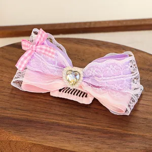 Détail du peigne à cheveux avec nœud rose et violet, dentelle et strass en cœur
