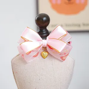 Gros plan du nœud en satin rose avec motifs de cœurs et pendentif cœur doré gravé