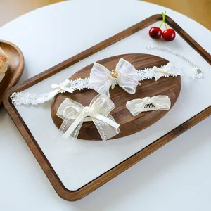 Detailed set of white lace dog collar, hair clip and comb with golden pearls on wooden tray
