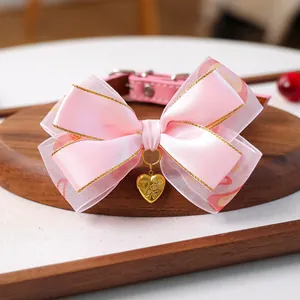 Détail du collier rose pour animal avec nœud en satin et pendentif cœur doré gravé