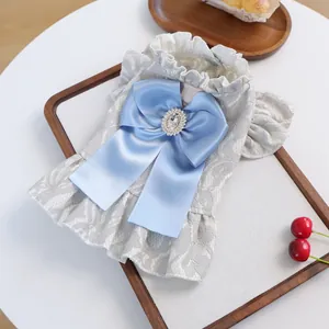 Close-up of pet dress showing grey lace fabric and blue satin bow with rhinestone