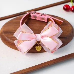 Détail de collier rose pour animaux avec nœud à cœurs et pendentif cœur doré