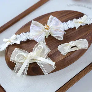 Close-up of cream lace pet bow set with pearls and ribbons on an oval wooden tray
