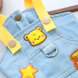 Macro shot of denim pet dress featuring embroidered bear patch and metal D-ring attachment