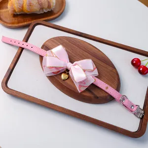 Détail du collier rose pour animal avec nœud en soie et pendentif cœur doré sur bois