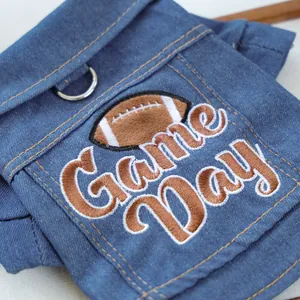 Detail view of the Game Day embroidery and metal D-ring on this blue denim pet vest