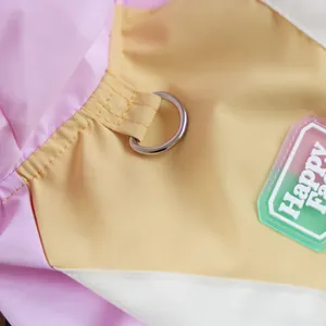 Detail of pink and yellow pet raincoat with a metal D-ring and Happy Face rubber patch