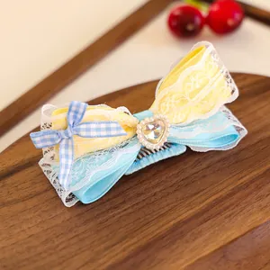 Détail de la pince à cheveux ruban jaune et bleu pour animaux avec dentelle et strass