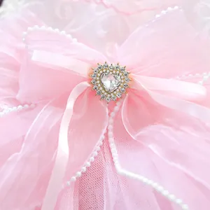 Close-up of pink organza bow with heart-shaped crystal and pearls for pet dress
