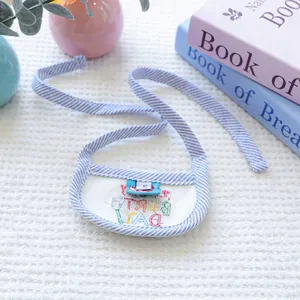 Detail of blue striped pet bib with rainbow embroidery and size tag on white background