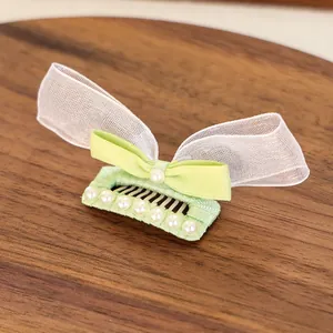 Détail d'une pince à cheveux avec nœud en satin vert, organza et perles élégantes