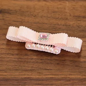 Close-up of pink ribbon bow hair clip with faux gemstone and pearls for small pets