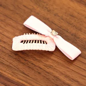 Detail of pink ribbon bow hair clip for small pets featuring a sparkling rhinestone heart