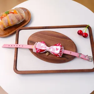 Détail du collier rose pour animal avec nœud multicouche et pendentif cœur doré
