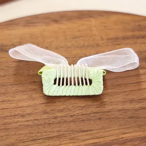 Gros plan d'une barrette verte pour chien avec des ailes de papillon en maille blanche