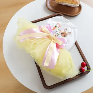 Detail of Easter pet dress with rabbit embroidery and yellow tulle skirt on wooden tray