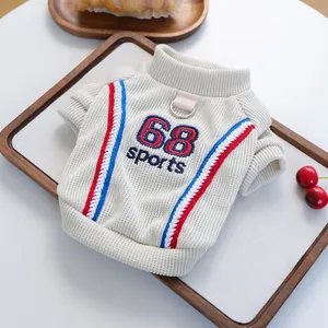 Detail of white knit pet sweater with '68 sports' embroidery and leash D-ring attachment
