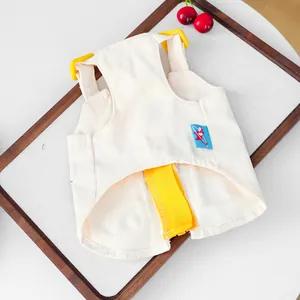 Detail view of cream white denim pet harness vest with yellow straps and buckle closure