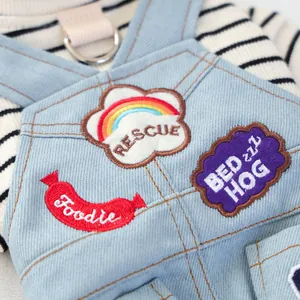 Dettaglio della salopette di jeans per animali con toppe arcobaleno e anello a D in metallo