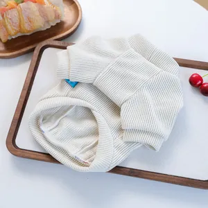 Detail of cream rib-knit pet sweater showing soft texture and elastic cuffs on a tray