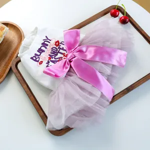 Easter bunny tulle dog dress with purple mesh skirt and pink satin bow on wooden tray